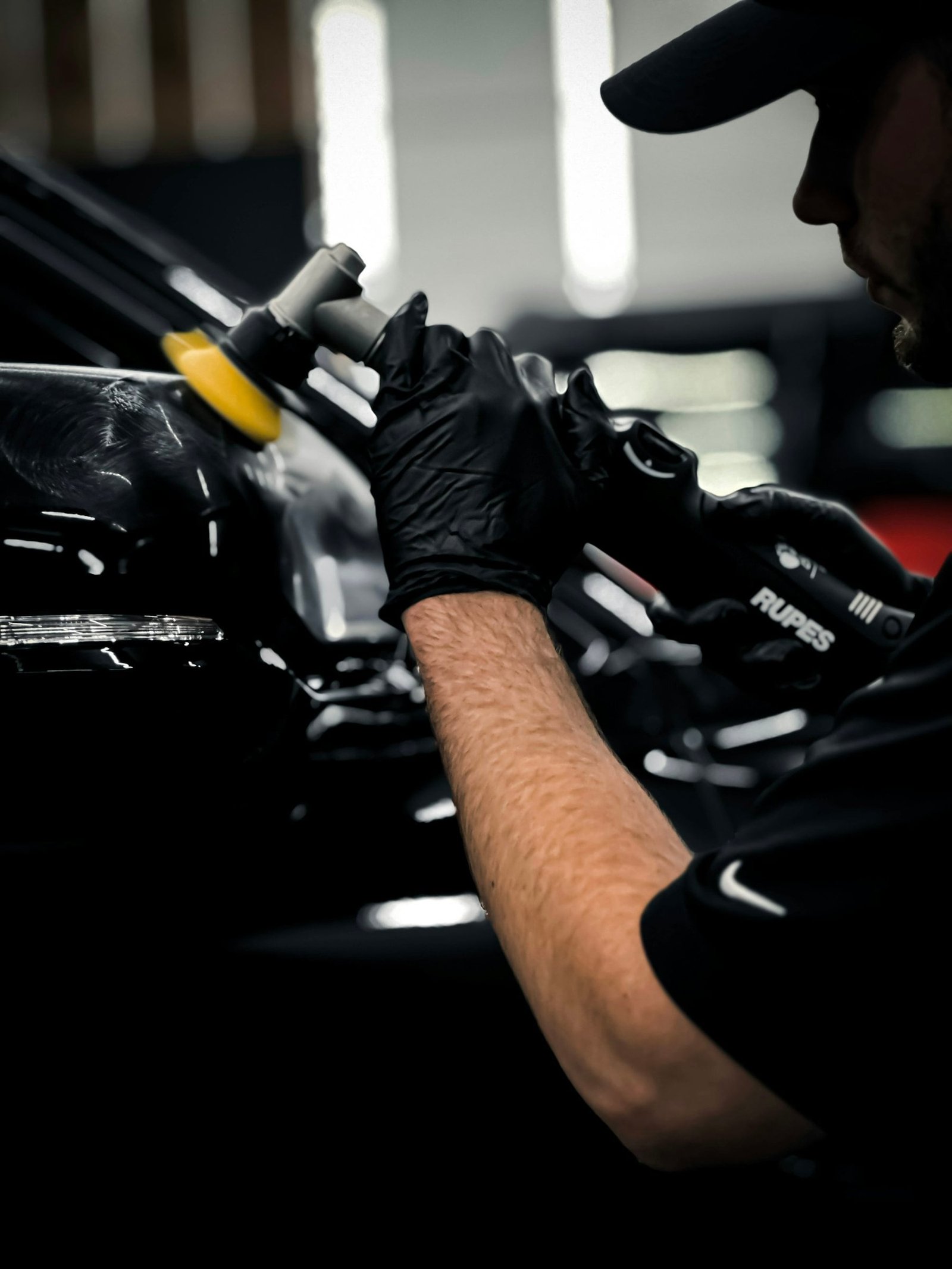 Technician polishing a black vehicle before film installation