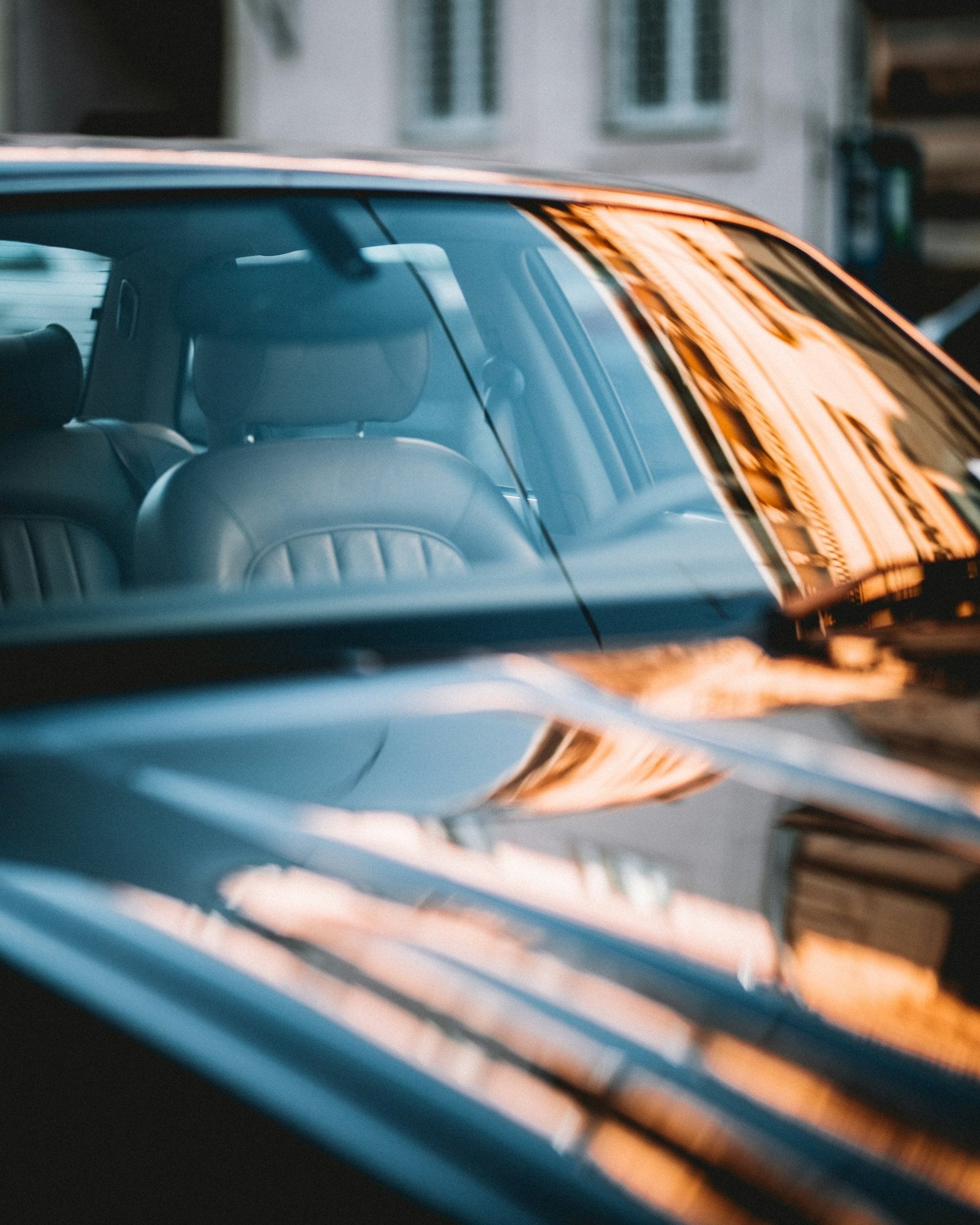 Sunset reflections across the dark tinted glass and glossy paint of a black car